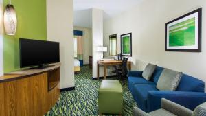 a hotel room with a blue couch and a tv at Holiday Inn Express & Suites Midland South I-20, an IHG Hotel in Midland