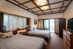 a hotel room with two beds and a flat screen tv at Baikoen in Fukuoka