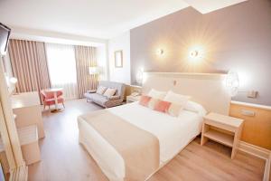 una camera d'albergo con un grande letto bianco e una sedia di Hotel Alfonso VIII a Soria