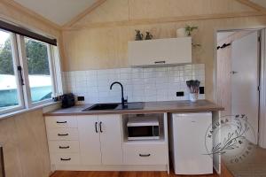 uma cozinha com armários brancos, um lavatório e um fogão em Kanuka Cottage em Whitianga
