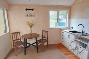 a kitchen with a table and two chairs and a sink at Kanuka Cottage in Whitianga