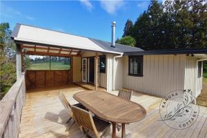 una terrazza in legno con tavolo e sedie su una casa di Kanuka Cottage a Whitianga Altre 8 foto