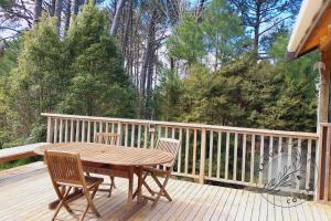 a wooden deck with a wooden table and chairs at Kanuka Cottage in Whitianga