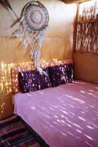 a bed with purple sheets in a room at Fully equipped Remote off-grid Solar Wooden Home in Dahab