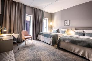 une chambre d'hôtel avec deux lits et une chaise dans l'établissement Hotel Odeon, à Odense