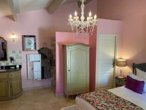 a bedroom with pink and green walls and a chandelier at Le Pré de l'Aube in Montjoyer
