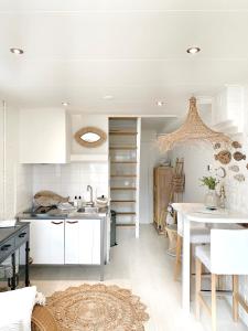 a kitchen with white cabinets and a table at ELSK Cottage in Zandvoort
