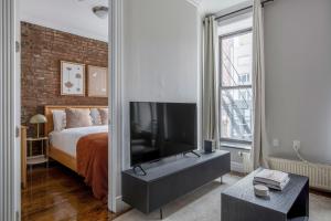 1 dormitorio con 1 cama, TV y pared de ladrillo en East Village 2br w wd nr groceries NYC-1221 en Nueva York