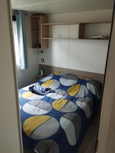 a bedroom with a bed with a blue and yellow comforter at MOBIL HOME in Piriac-sur-Mer