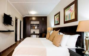 a bedroom with a large white bed and a television at @The Villa Guest House in Bloemfontein