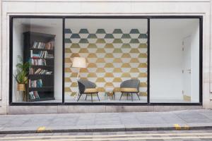 ein Lagerfenster mit zwei Stühlen und einem Bücherregal in der Unterkunft Aparthotel Adagio Liverpool City Centre in Liverpool