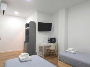 a room with two beds and a desk and a tv at Casa de Huéspedes 12 Octubre Rooms in Madrid