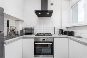 a white kitchen with a stove and a sink at Kasprowicza 15 by Homeprime in Warsaw