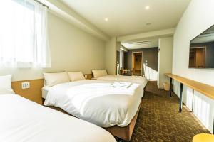 a hotel room with three beds and a television at CVS Bay Hotel in Urayasu