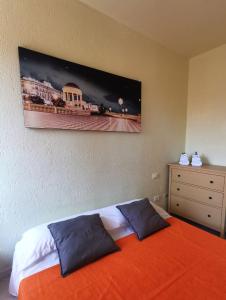 a bedroom with a bed with an orange blanket and a dresser at Essenza del Mare Home in Livorno