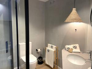 Łazienka z białą toaletą i umywalką w obiekcie Calendula Hotel w Sant Feliu de Guixols