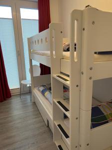 ヴァンガーオーゲにあるLüttje Oog - Moderner und behaglicher Komfort für 4 Personen auf 59 m²の二段ベッド2台とベッド1台が備わる客室です。
