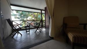 einen Balkon mit 2 Stühlen, einem Tisch und einem Fenster in der Unterkunft Samawa Transit Hotel in Sumbawa Besar