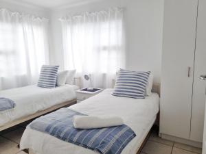 een slaapkamer met 2 bedden met gestreepte kussens erop bij Pearly Gate in Pearly Beach