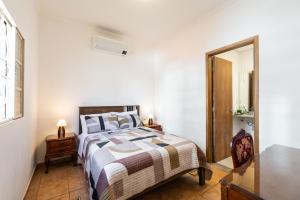 ein weißes Schlafzimmer mit einem Bett und einem Spiegel in der Unterkunft Casa da Cris in São Paulo