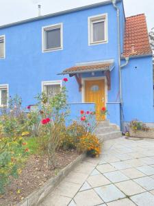 una casa azul con una puerta amarilla y algunas flores en Family-friendly House in Vienna's Suburbs!, en Guntramsdorf