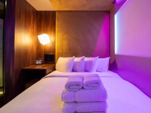 a bedroom with a bed with purple lights on it at Bloc Hotel London Gatwick Airport in Horley