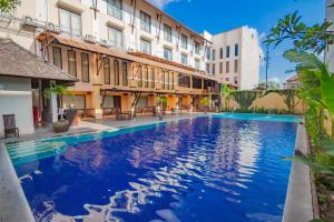 a swimming pool in front of a building at Grand Santhi Hotel in Denpasar