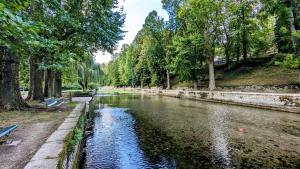 a river in a park with a bench and trees at La Tuilerie in Bèze