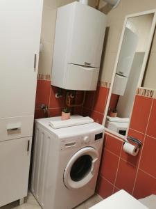 - un lave-linge dans la salle de bains pourvue de carreaux rouges dans l'établissement Apartman Ines - Osijek, à Osijek