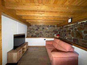 sala de estar con sofá y pared de piedra en Cabaña Pasiega Castro Valnera, en Vega de Pas