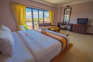 a bedroom with a large bed and a balcony at Grand Santhi Hotel in Denpasar