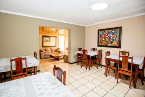 a dining room with tables and chairs and a painting on the wall at Oria Lodge in Cape Town