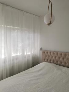 - une chambre avec un lit et une fenêtre avec des rideaux blancs dans l'établissement Apartman Ines - Osijek, à Osijek