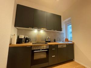 a kitchen with black cabinets and a stove top oven at Central•Balcony•Messe•Uniklinik perfect for 2 in Essen