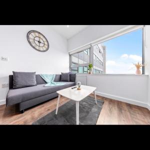 uma sala de estar com um sofá, uma mesa e um relógio em Charming 1 Bedroom Flat in Essex TH620 em Basildon