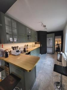 une cuisine avec des placards verts et un comptoir en bois dans l'établissement Superbe 100 M2, 4 chambres, à Sainte-Foy-lès-Lyon