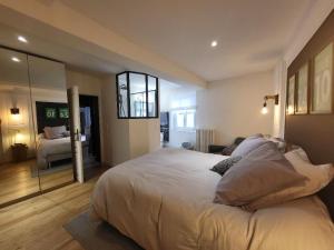 - une chambre avec un grand lit et un miroir dans l'établissement Superbe 100 M2, 4 chambres, à Sainte-Foy-lès-Lyon