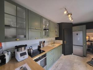 La cuisine est équipée de placards verts et d'un réfrigérateur blanc. dans l'établissement Superbe 100 M2, 4 chambres, à Sainte-Foy-lès-Lyon