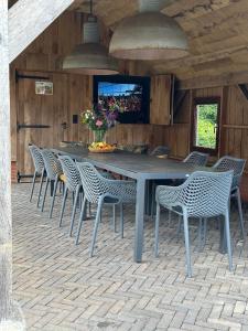 een grote tafel met stoelen en een televisie aan de muur bij Scholtefleer in De Lutte