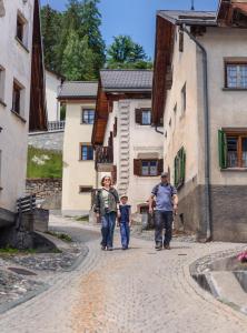 two adults and a child walking down a cobblestone street at Chasa Fent, Sent Scuol im Engadin in Scuol