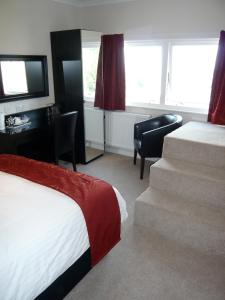 a hotel room with a bed and a desk and a television at Queenswood Hotel in Weston-super-Mare