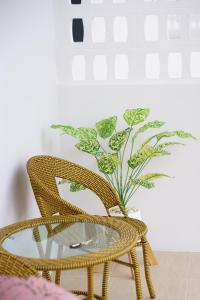 two wicker chairs and a glass table with a plant at Chanmuang Resort ชานเมืองรีสอร์ท in Phetchaburi