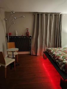 1 dormitorio con cama y mesa con luz roja en Chez Stéphanie et Sylvain, en Le Mesnil-Villeman