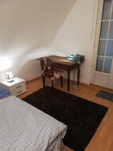 Zimmer mit einem Schreibtisch mit einem Stuhl und einem Bett in der Unterkunft Gîte Au nid de cigognes in Leutenheim