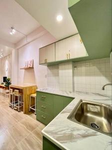 uma cozinha com armários verdes e um lavatório de aço inoxidável em JORA LOFT - Japandi inspired apt 1- D em Dagupan