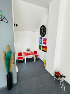 a room with a table and red chairs and a clock at Kata Place Hotel in Kata Beach