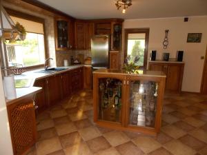 a large kitchen with wooden cabinets and a refrigerator at Domek pod Lasem na Mazurach in Ryn