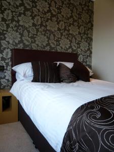a bedroom with a bed with white sheets and pillows at Queenswood Hotel in Weston-super-Mare