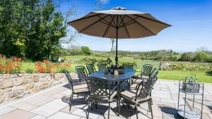 a table and chairs with an umbrella on a patio at Pen y Fan Bellaf in Llanddyfnan