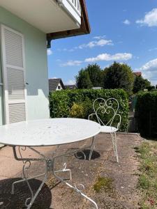 a white table and chairs sitting next to a house at Gîte Au nid de cigognes in Leutenheim
